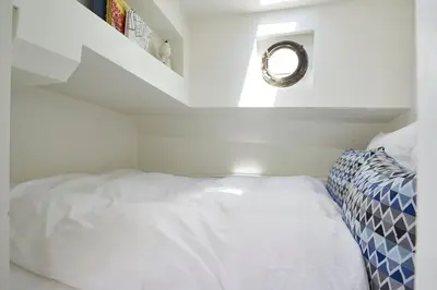 a small bedroom with a white bed and a staircase at Luxurious 110m² 3br Houseboat in Amsterdam Centre! in Amsterdam