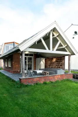 a house with a large roof with a patio at Klein Polderhuis - tuinhuis in Roelofarendsveen