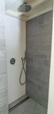 a shower in a bathroom with a shower head at Klein Polderhuis - tuinhuis in Roelofarendsveen