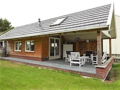 a small house with a porch with chairs and tables at Klein Polderhuis - tuinhuis in Roelofarendsveen