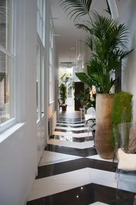 a hallway with black and white floors and plants at Boutiquehotel Staats in Haarlem