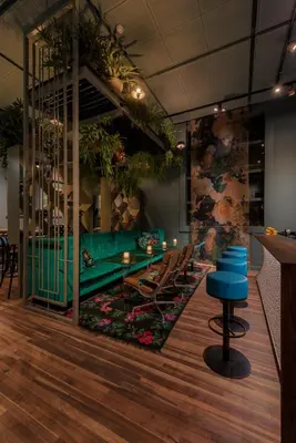 a restaurant with a green table and chairs on a rug at Boutiquehotel Staats in Haarlem