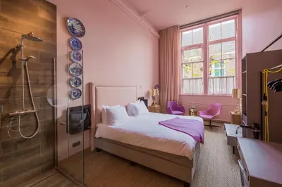 a bedroom with a bed and a glass shower at Boutiquehotel Staats in Haarlem