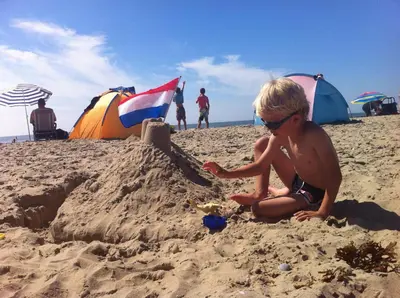 a young boy playing in the sand on the beach at 