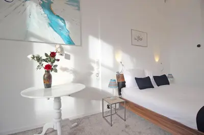a white bedroom with a bed and a table with flowers at Cozy Jordaan canalhouse near Anne Frank House in Amsterdam