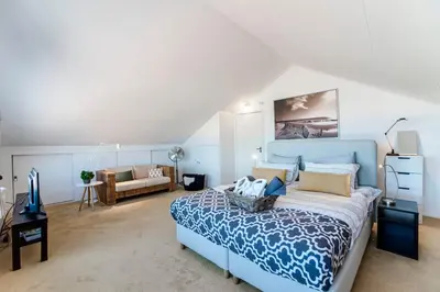 a bedroom with a blue bed and a couch at Villa 't Spokeduin in Zandvoort