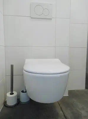 a white toilet in a white tiled bathroom at Duinkant in Groet