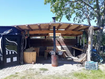 a wooden pergola with a table and a swing at Duinkant in Groet