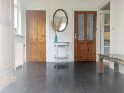 a hallway with a wooden door and a mirror at Duinkant in Groet