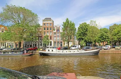 a boat is docked on a river in a city at Romantic Jordaan Canalsuite near Anne Frank House in Amsterdam