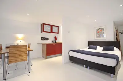 a bedroom with a bed and a desk and a kitchen at Romantic Jordaan Canalsuite near Anne Frank House in Amsterdam