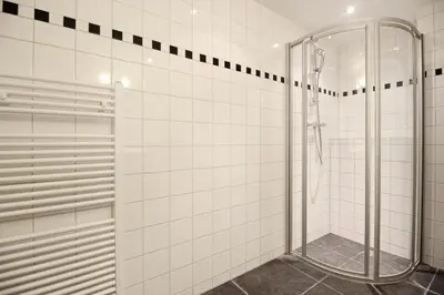 a glass shower in a white tiled bathroom at Romantic Jordaan Canalsuite near Anne Frank House in Amsterdam