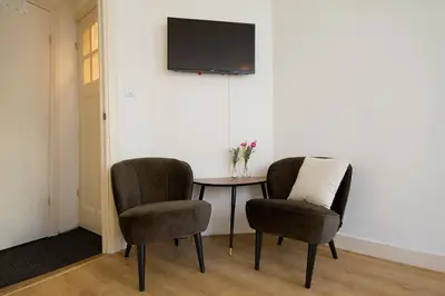 two chairs and a table with a tv on a wall at Spui's the Limit in Amsterdam