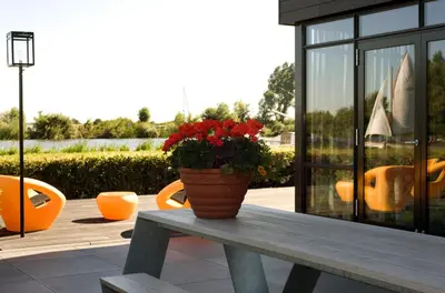 a pot of red flowers sitting on a wooden bench at als het golft in Roelofarendsveen