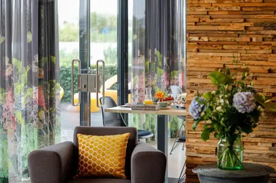a room with a table and a chair and a vase of flowers at als het golft in Roelofarendsveen