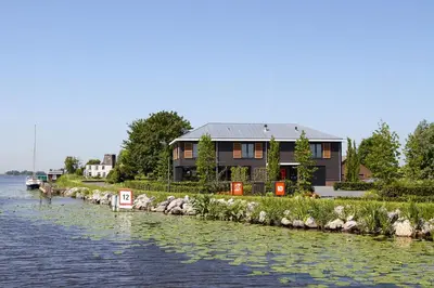 a house on the shore of a river at als het golft in Roelofarendsveen