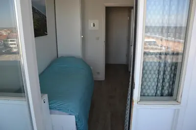 a small bed in a room with two windows at Beach Apartment Ikusasa in Zandvoort