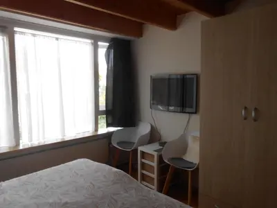 a bedroom with a bed and two chairs and a tv at Hetem's Room in Amsterdam