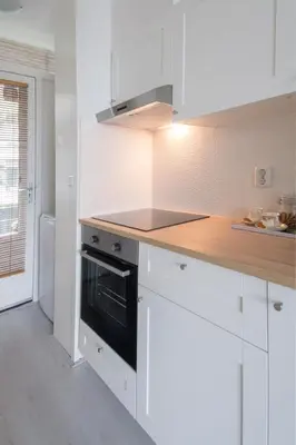 a kitchen with white cabinets and a stove top oven at Amsterdam Beach Apartment 80 in Zandvoort