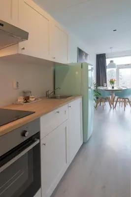 a kitchen with white cabinets and a blue refrigerator at Amsterdam Beach Apartment 80 in Zandvoort