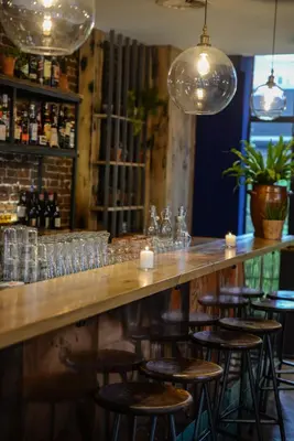 a bar with a long wooden counter with stools at Chasse Boutique Hotel in Amsterdam