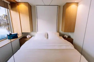 a bedroom with a large white bed and a window at The Amsterdam Houseboat Family - de Jordaan Brand New Houseboat! in Amsterdam