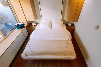 a small bedroom with two beds and a window at The Amsterdam Houseboat Family - de Jordaan Brand New Houseboat! in Amsterdam