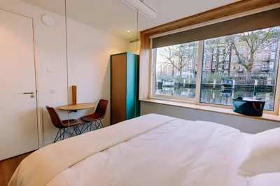 a bedroom with a bed and a window and a table at The Amsterdam Houseboat Family - de Jordaan Brand New Houseboat! in Amsterdam