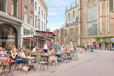 a group of people sitting at tables and chairs in front of a building at City Attic Haarlem in Haarlem