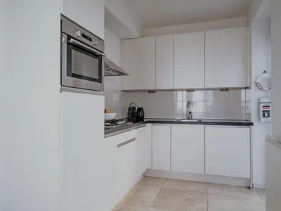 a white kitchen with white cabinets and a microwave at Apartment in Egmond aan Zee near the Beach in Egmond aan Zee