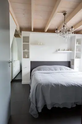 a white bedroom with a bed and a chandelier at Vakantiehuis Olivia in Schoorl