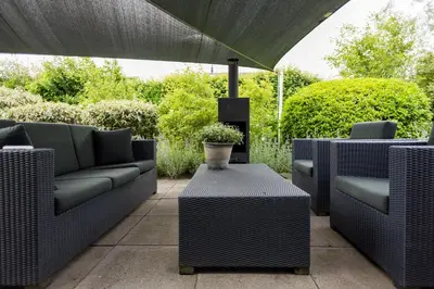 a patio with couches and a table and an umbrella at Vakantiehuis Olivia in Schoorl