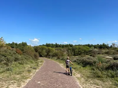 a young boy riding a bike down a dirt road at huize Louwra in Egmond-Binnen