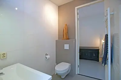 a white bathroom with a toilet and a shower at Zandstudio in Alkmaar