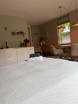 a large white bed in a room with a kitchen at Zandstudio in Alkmaar