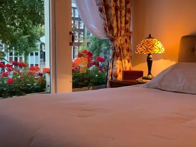 a bedroom with a bed and a window with flowers at Keizershouse Amsterdam in Amsterdam