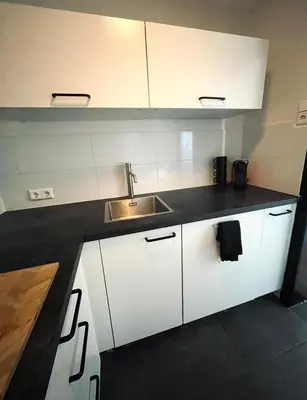 a kitchen with white cabinets and a sink at Apartment Marmoris in Zandvoort