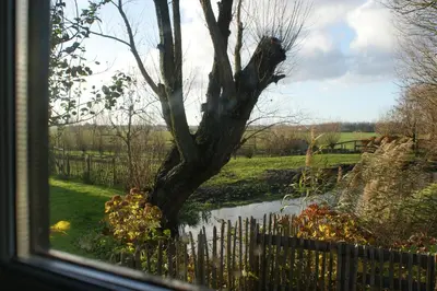 a window view of a tree and a fence at Hoeve Suydeinde in Aarlanderveen
