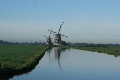 a windmill in a field next to a river at Hoeve Suydeinde in Aarlanderveen