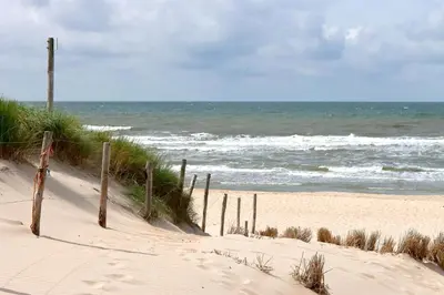a sandy beach with a fence and the ocean at Vakantiehuis Katwijk Andreasplein in Katwijk