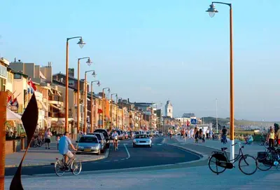 a busy city street with people riding bikes and cars at Vakantiehuis Katwijk Andreasplein in Katwijk