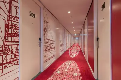 a corridor with a red carpet and drawings on the walls at Leonardo Hotel Vinkeveen Amsterdam in Vinkeveen