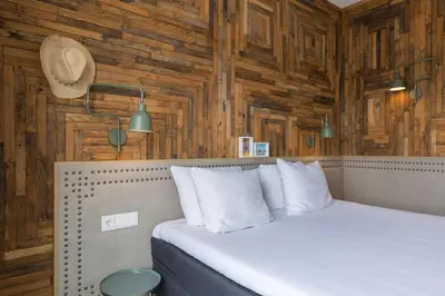 a bedroom with wooden walls and a bed with white pillows at Leonardo Hotel Vinkeveen Amsterdam in Vinkeveen