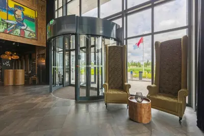 a lobby with two chairs and a glass elevator at Leonardo Hotel Vinkeveen Amsterdam in Vinkeveen