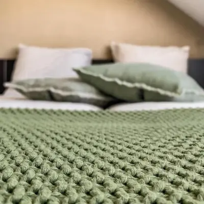 two beds with green comforters and pillows at B&B Mol in Katwijk aan Zee