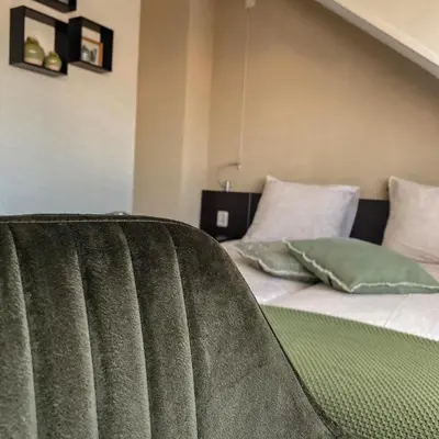 a bed with green and white pillows in a room at B&B Mol in Katwijk aan Zee