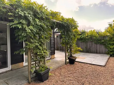 a garden with two trees in front of a house at Coast Holiday Appartements in Dirkshorn