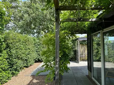 a garden entrance to a house with a pergola at Coast Holiday Appartements in Dirkshorn
