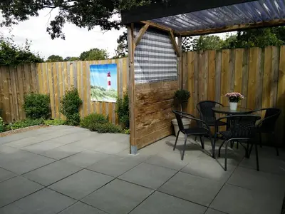 a patio with a table and chairs and a wooden fence at Coast Holiday Appartements in Dirkshorn