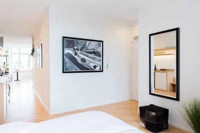 a white bedroom with a mirror on the wall at 2L Hof van Holland apartments in Noordwijk